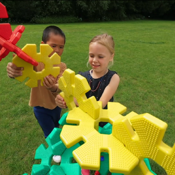 Dos niños construyen un vehículo de fantasía con discos de construcción Octoplay en el jardín.